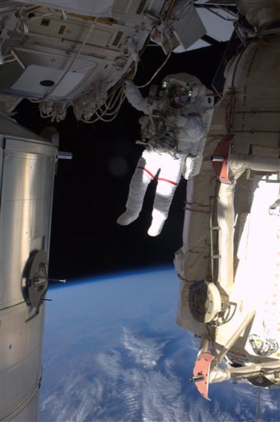 This image from NASA shows astronaut Andrew Feustel hanging by one arm from the International Space Station backdropped by the blue Earth during the mission's third spacewalk on Wednesday.